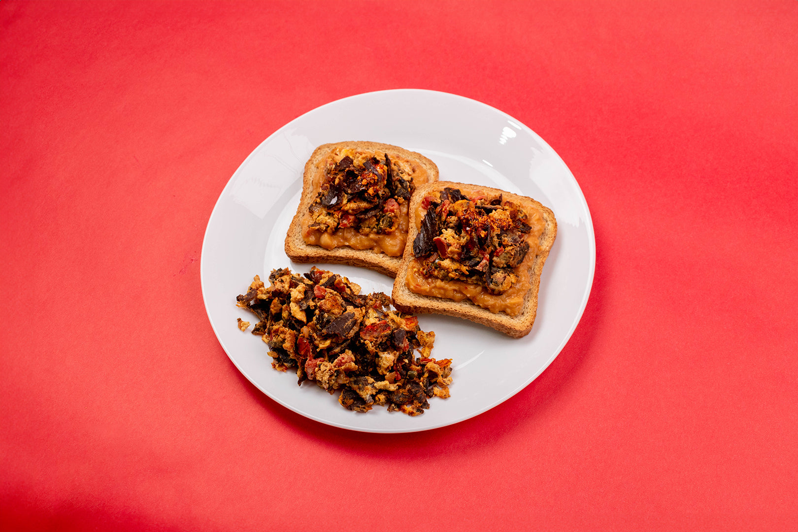 Dos rebanadas de pan tostado con frijoles y guisado de huevo con cecina.